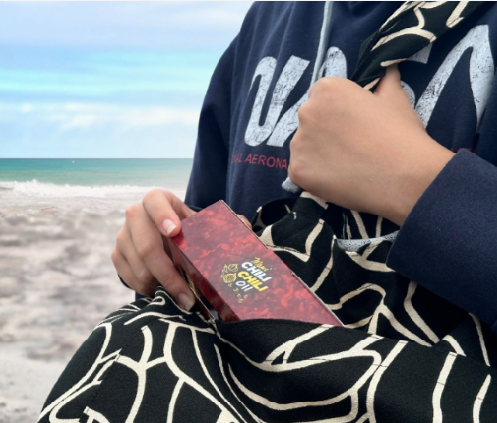 person at the beach with a red maui chili oil gift box