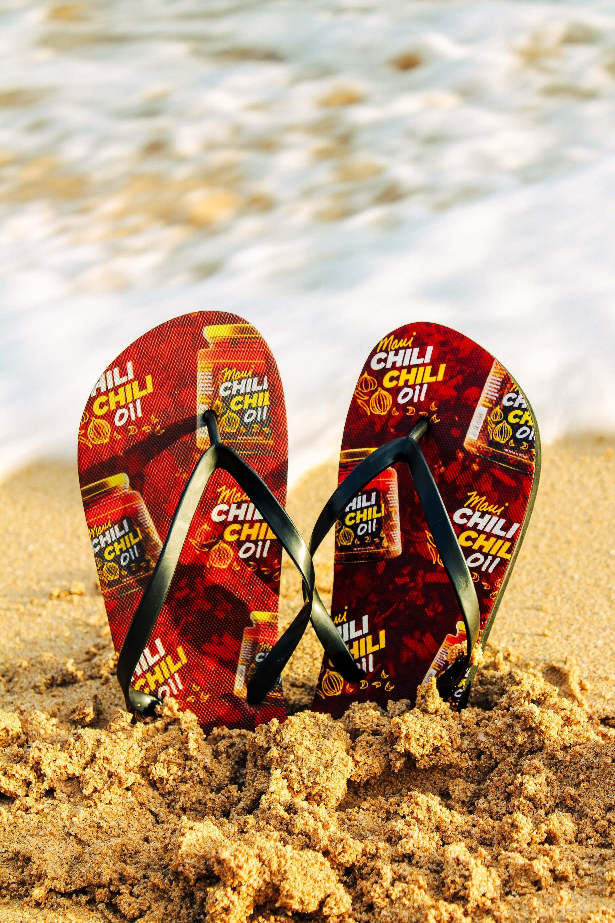 Flip-flops with chili oil branding on a sandy beach