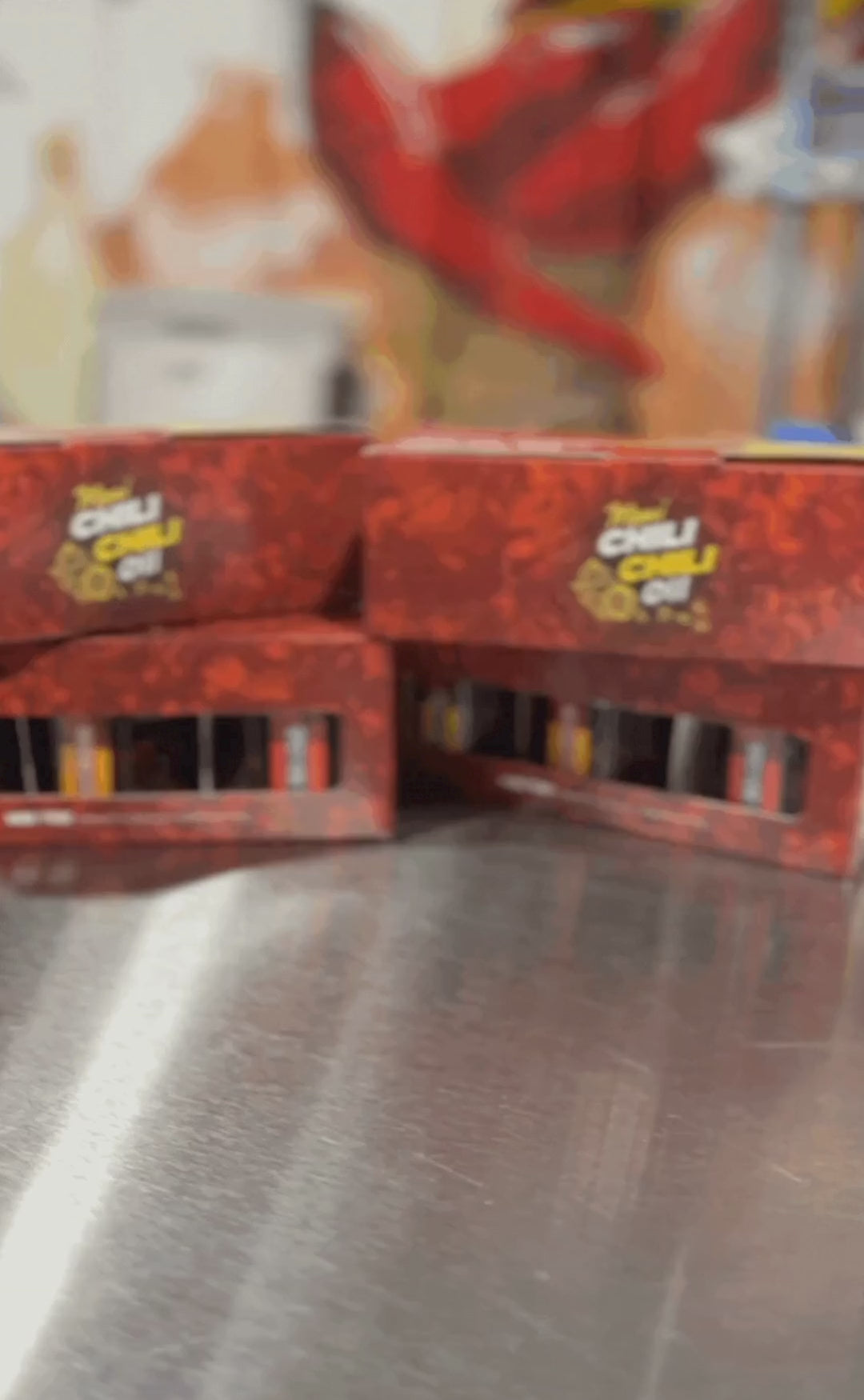 3 minis of Maui Chili Chili Oil sliding into the frame with gift boxes stacked in the background