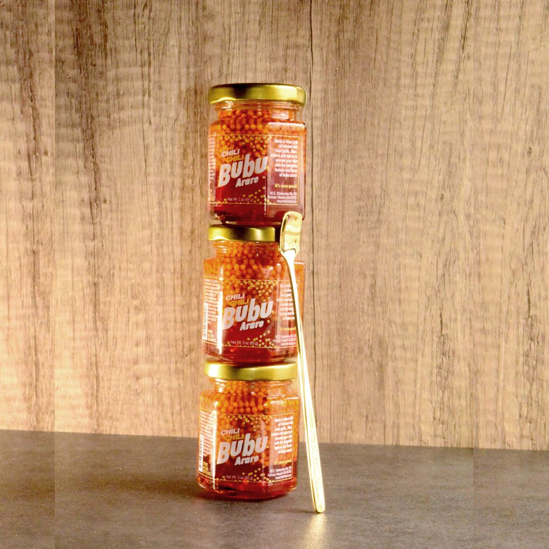 3 jars of bubu arare stacked with a gold spoon leaning against it