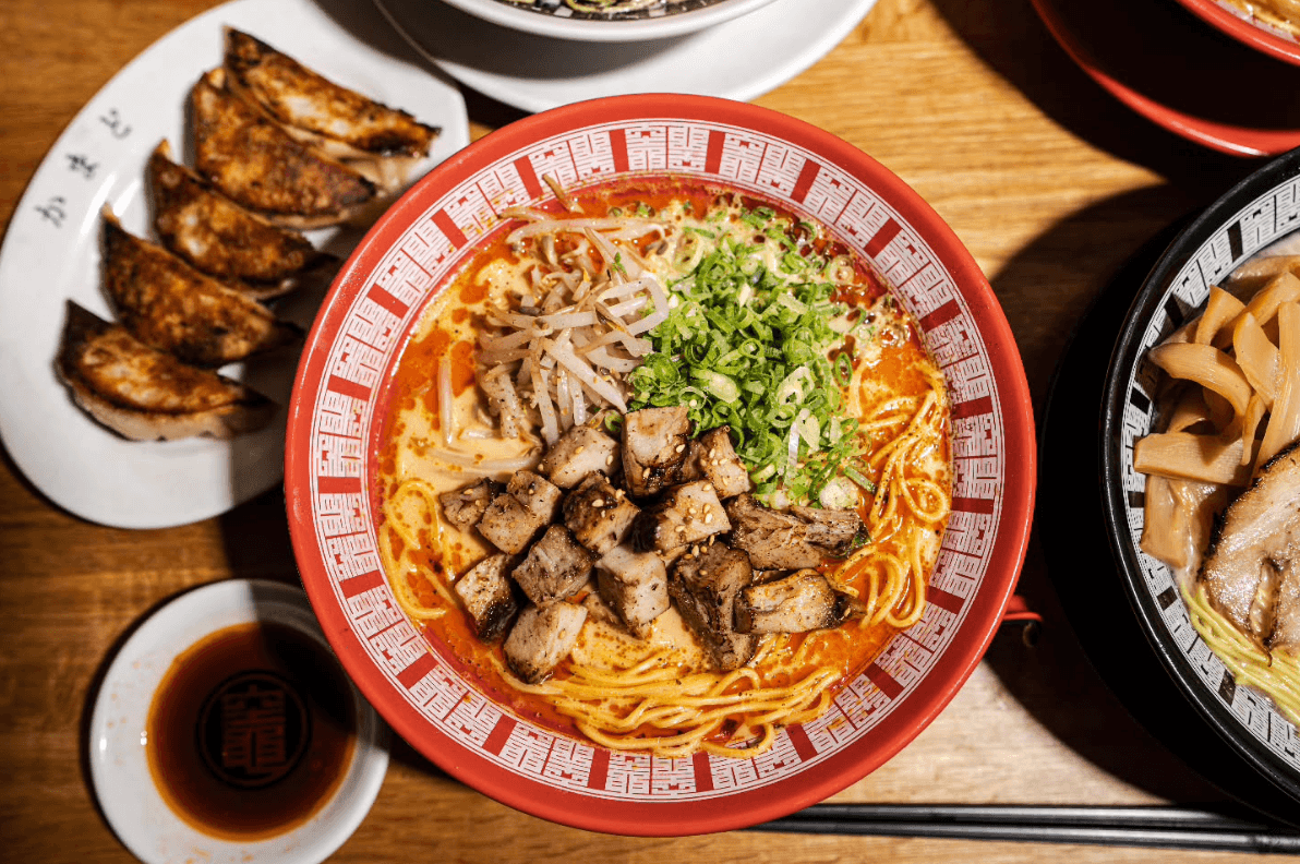 Bowl of noodles with meat and vegetables on a wooden table