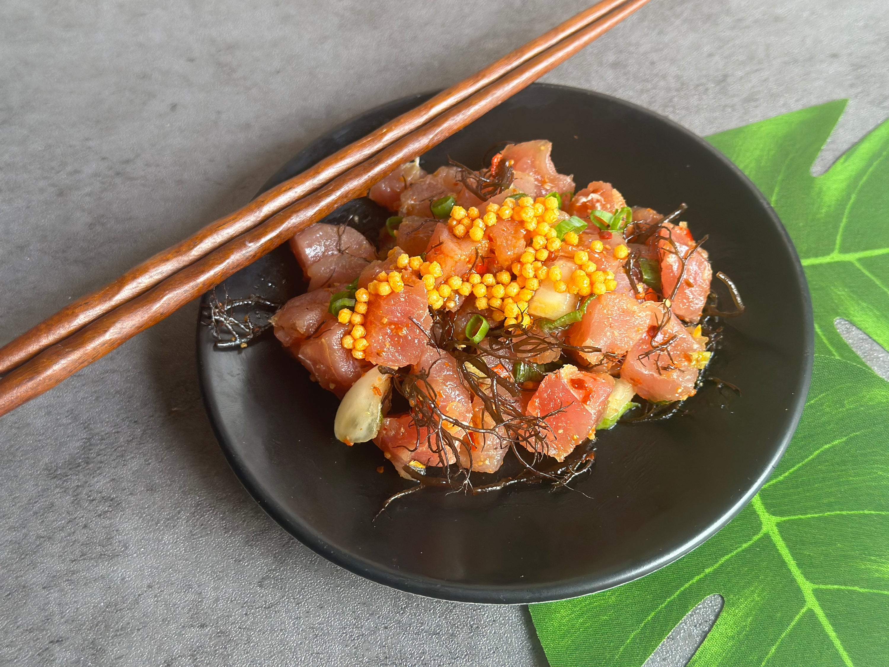 dish of poke with chop sticks on black plate