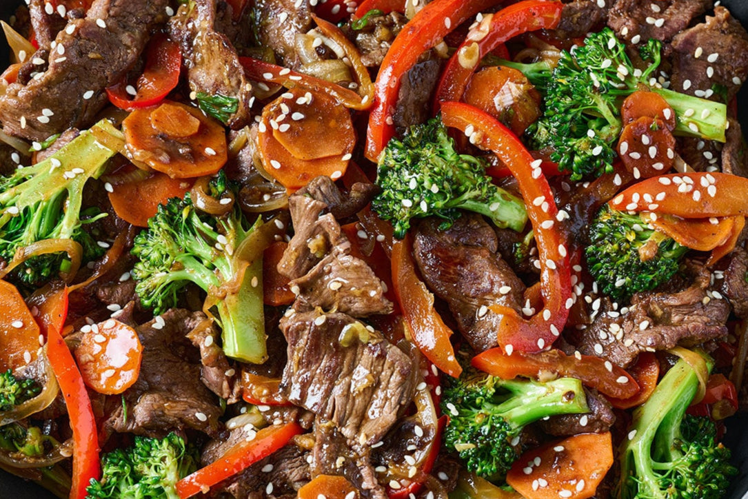 Stir-fried dish with beef, broccoli, carrots, and bell peppers on a plate.